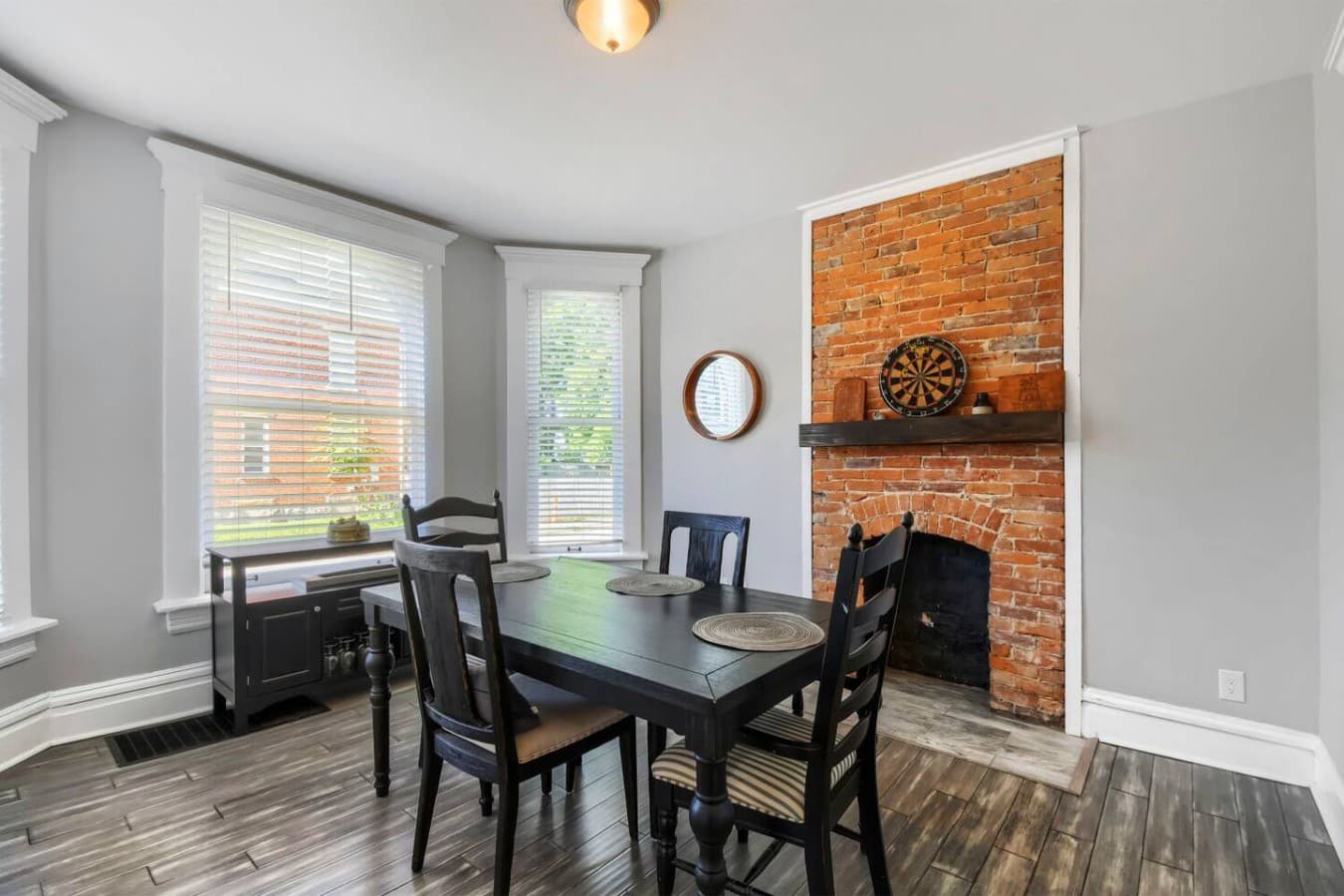 Enjoy meals beside the charming brick fireplace in this inviting dining space filled with natural light.