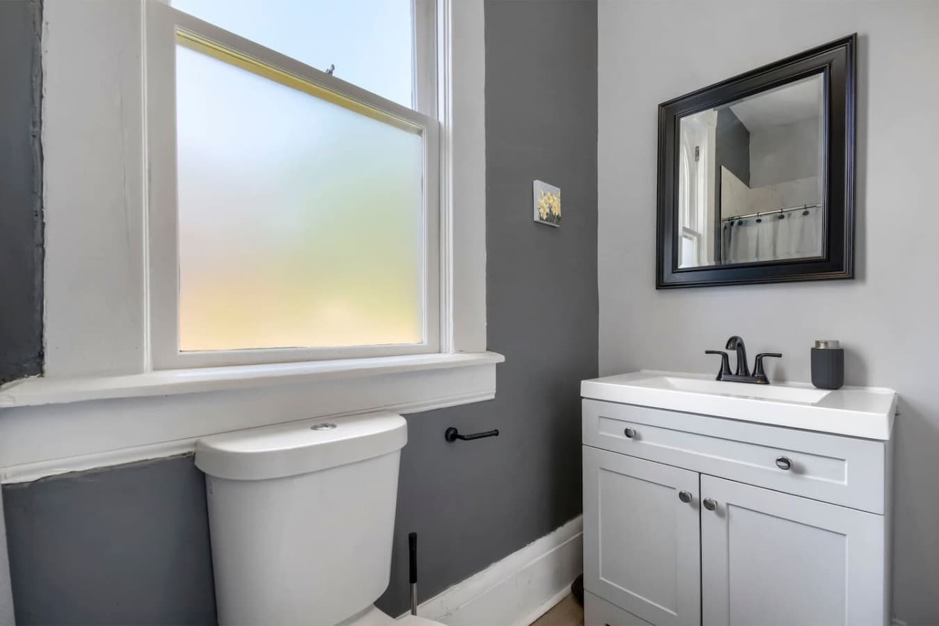 Clean and modern bathroom with a bright vanity, large mirror, and natural light.
