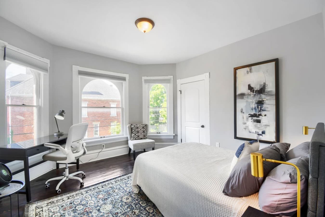 Relax in a spacious bedroom featuring a comfortable bed, dedicated workspace, and beautiful natural light.