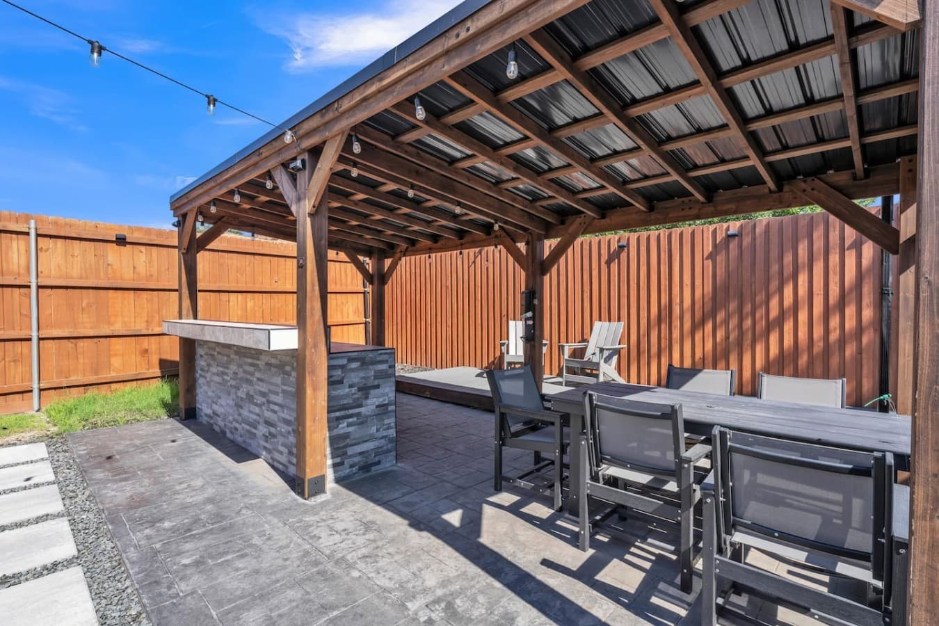 Spacious backyard entertainment area featuring a shaded pergola, outdoor dining, and room to relax year round.