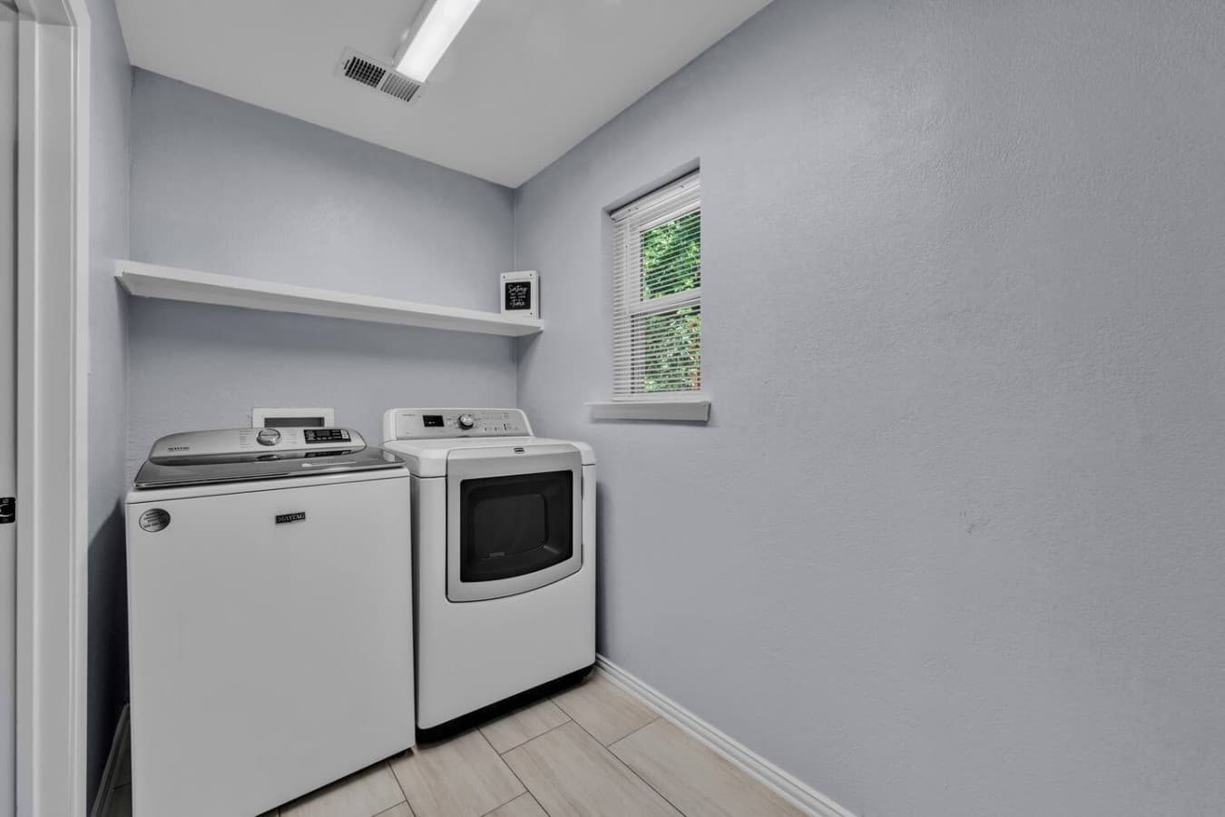 Bright and functional laundry space stocked with essential appliances and extra shelving for added convenience.