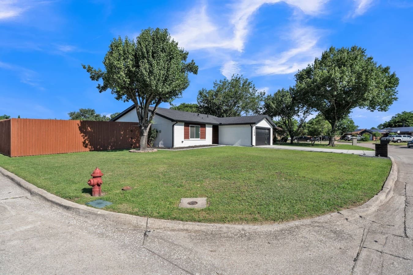Corner lot setting with a large front yard and mature trees that add space, privacy, and charm.