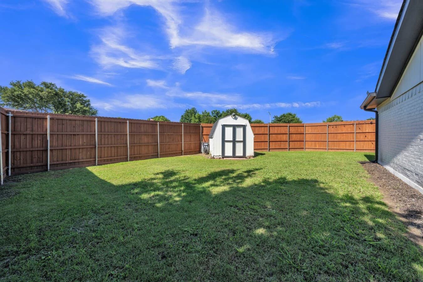 Large fenced backyard with plenty of open green space for outdoor games, family fun, and relaxing in the sunshine.