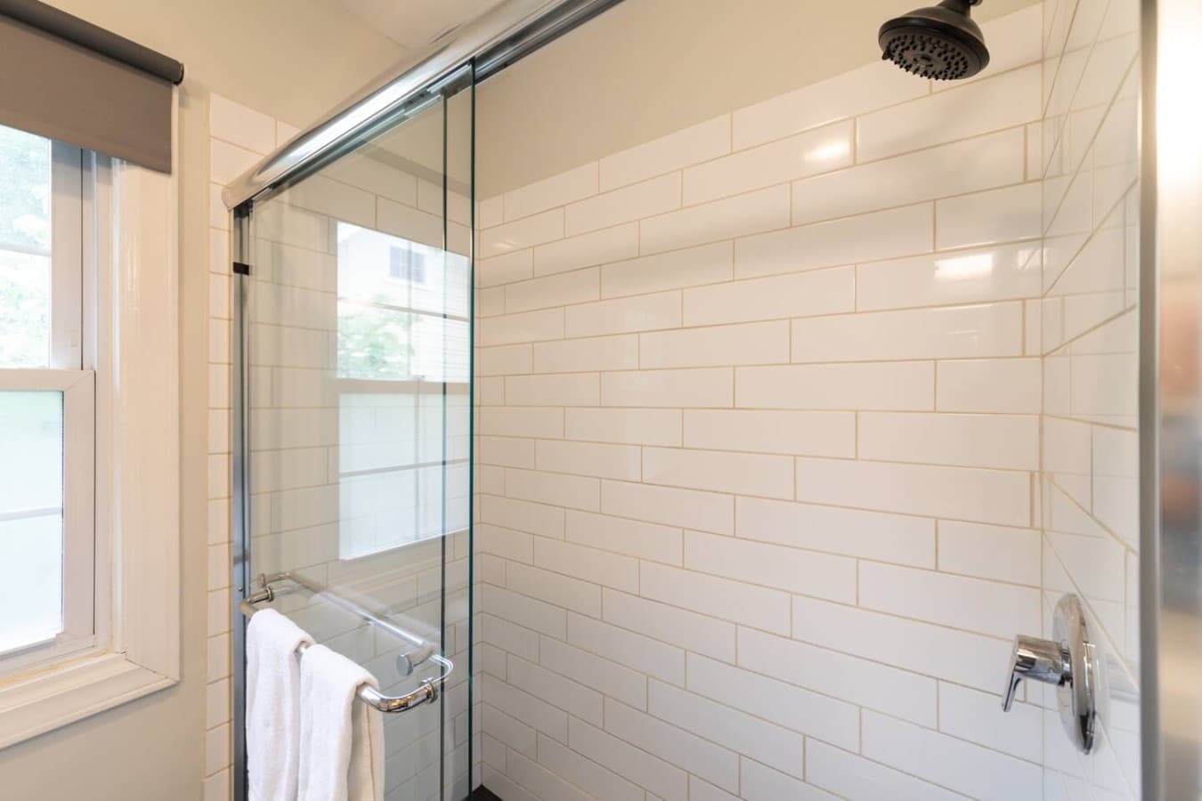 Spacious walk in shower featuring sleek subway tile and contemporary finishes.