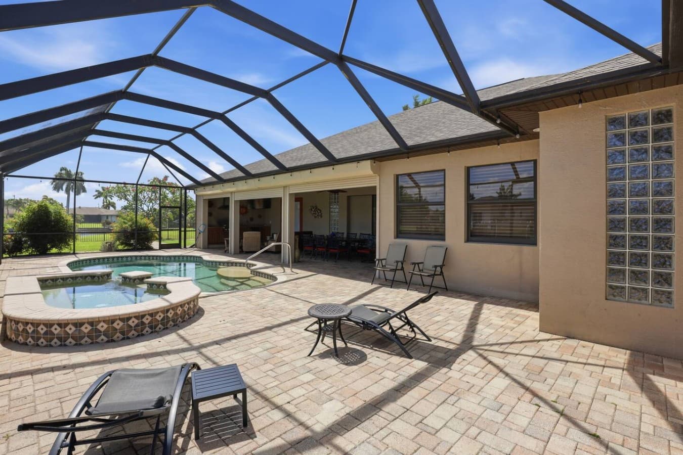 Resort style pool deck with comfortable lounge seating and covered patio access.