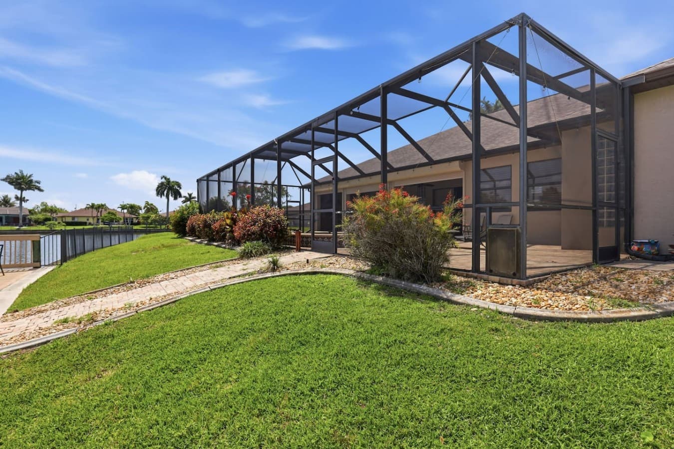Large screened outdoor enclosure with lush landscaping and waterfront surroundings.