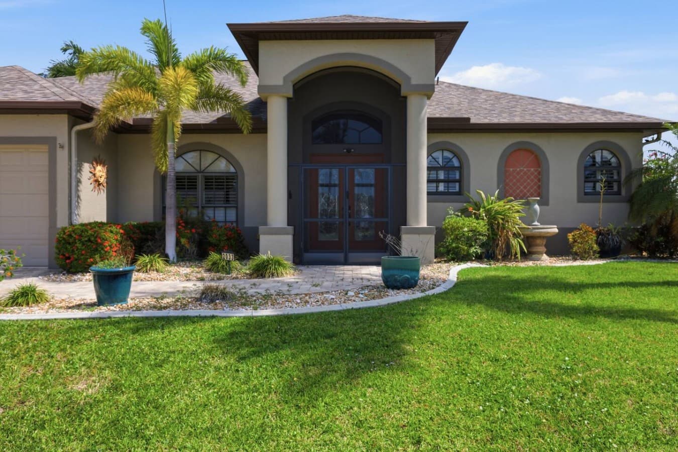 Grand front entrance with beautiful architectural details and tropical landscaping.