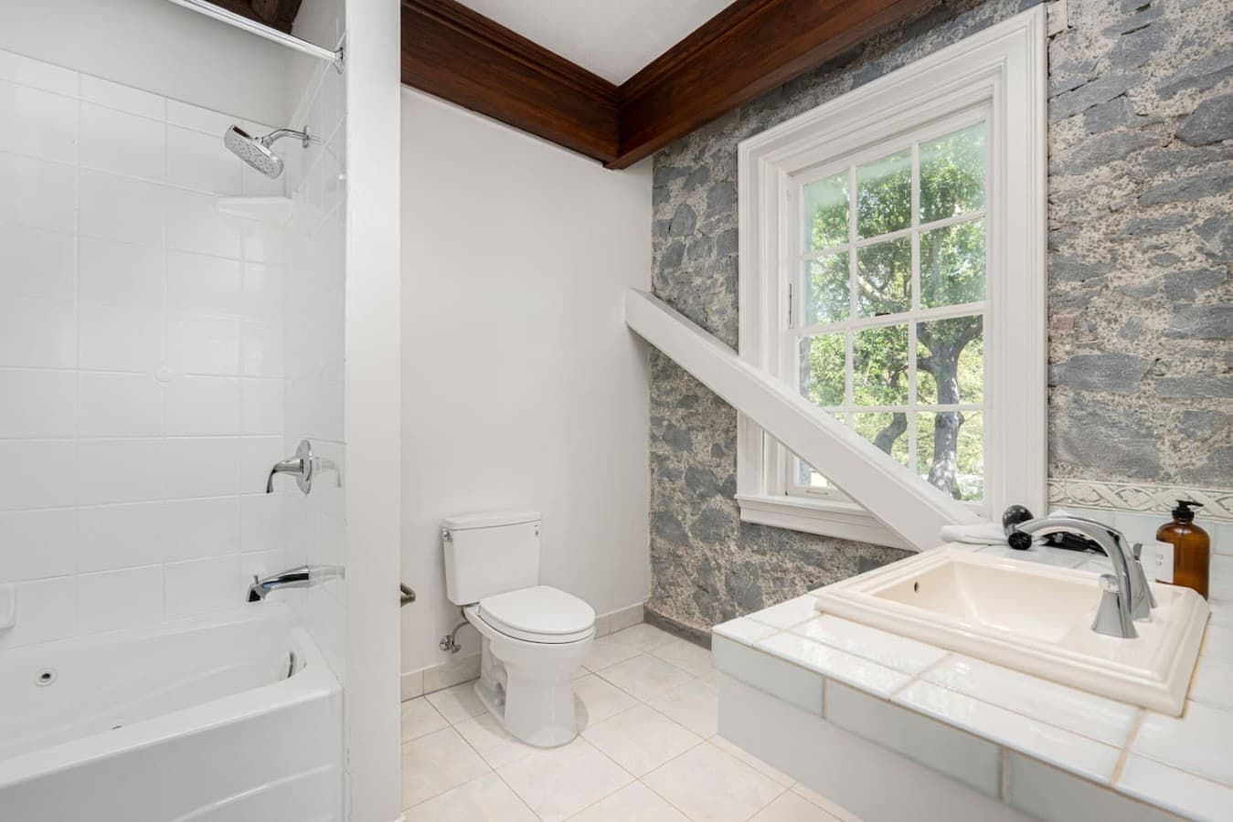 This is the private bathroom inside the room you will be renting featuring a clean shower and tub combination, stone-accented walls, and bright natural light.