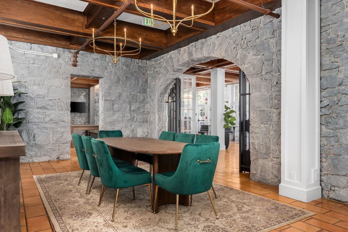 A shared gathering space with a large communal table and artistic stone walls located in the hotel’s common area and not inside your private room.