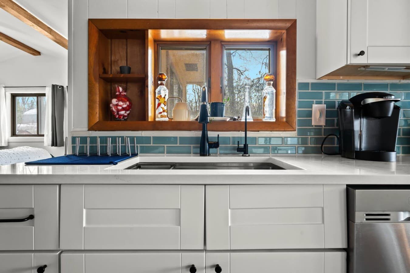Clean sink area with a window view and stylish backsplash.