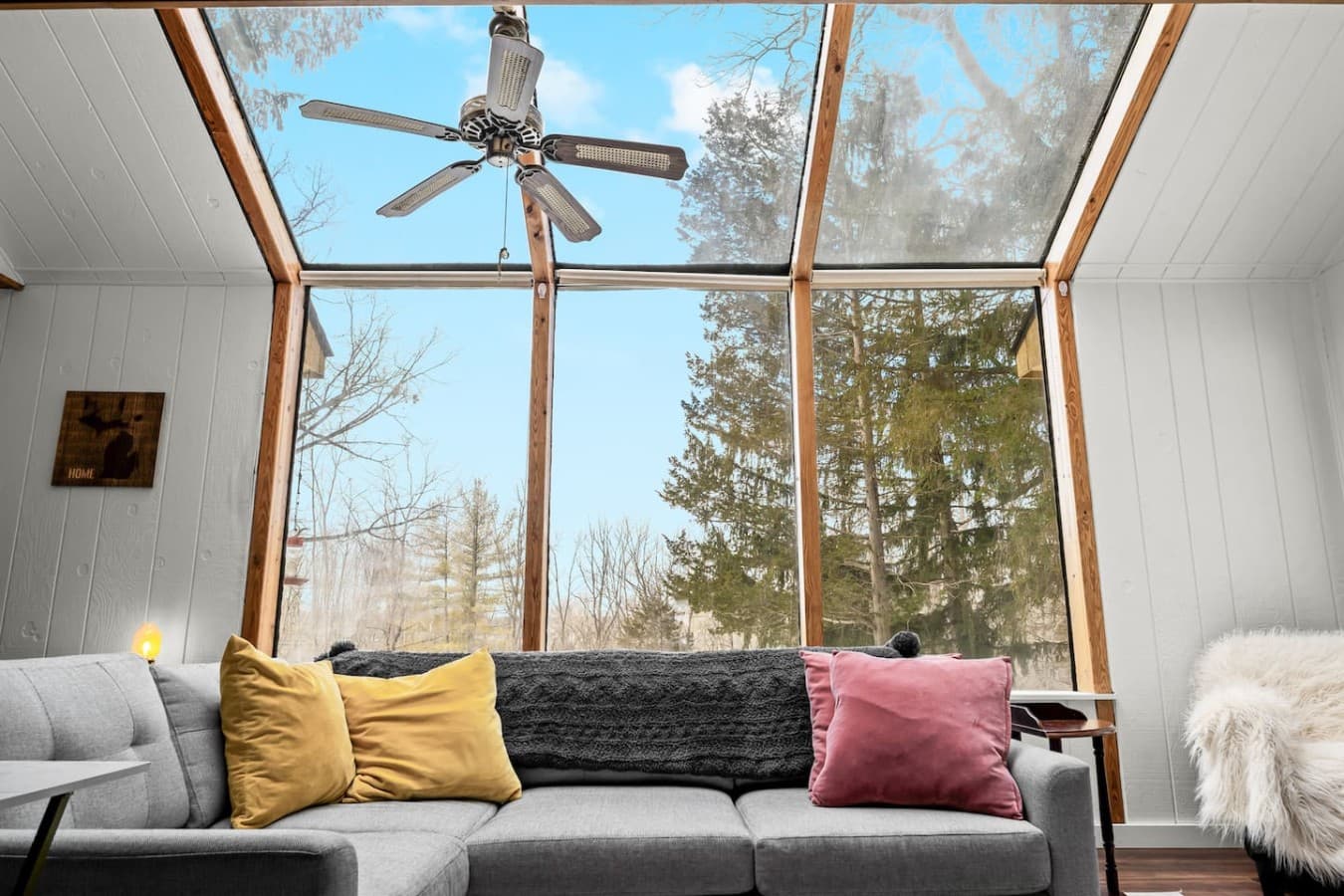 Sunroom style lounge with floor to ceiling windows and forest views.