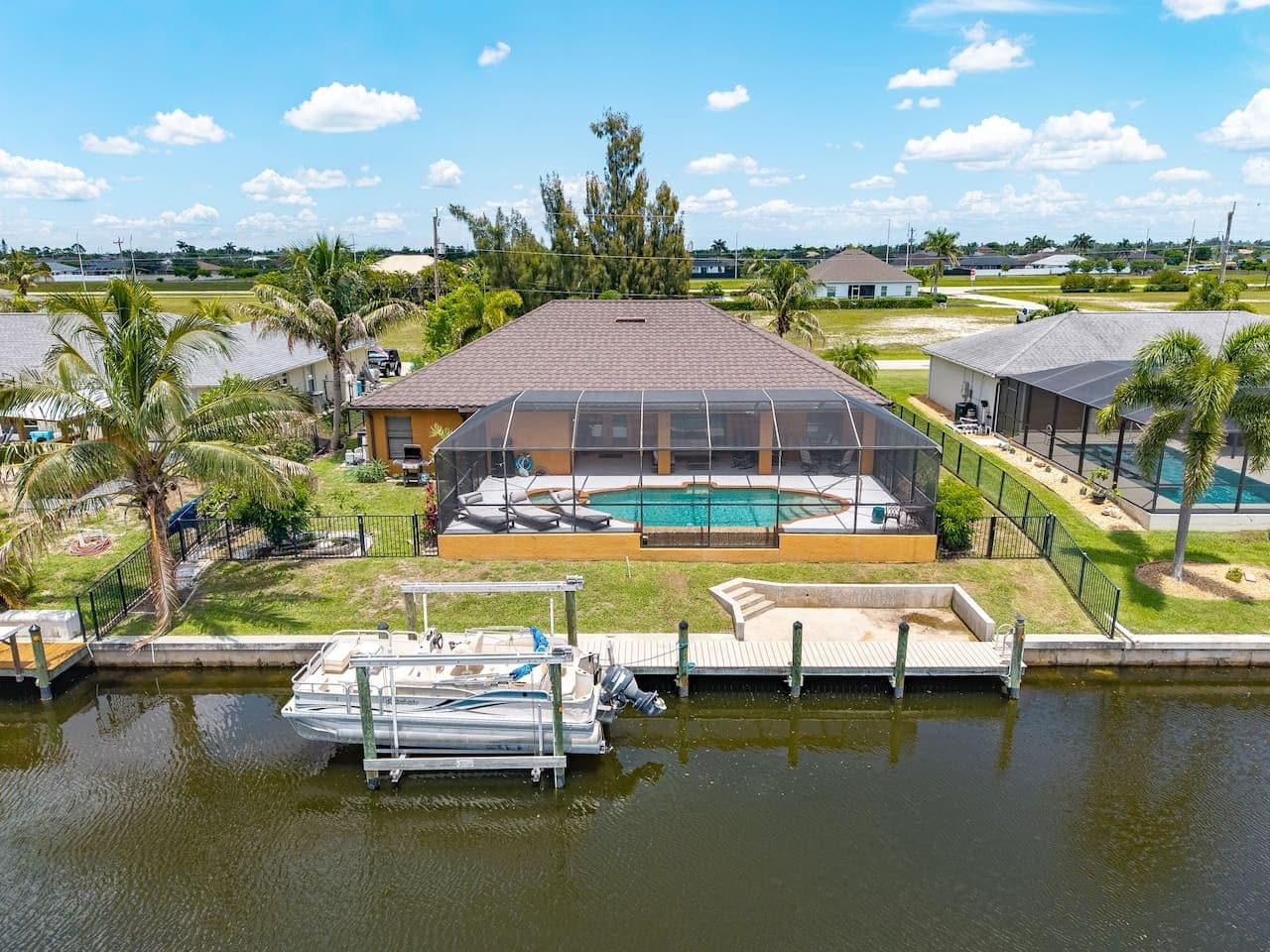 Aerial view showcasing the screened pool, private dock, and beautiful canal frontage.