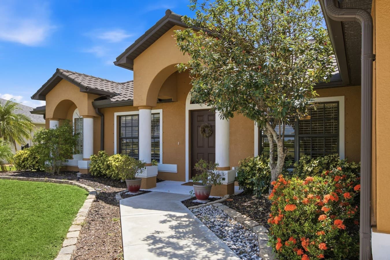 Inviting covered front entry with elegant architectural details and mature landscaping.