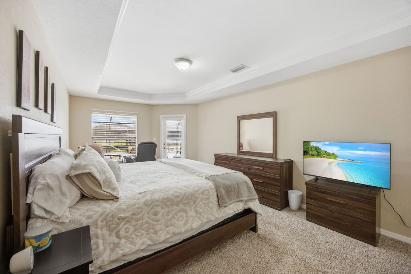 Bright primary suite featuring a king-sized bed, dresser, and cozy sitting area.