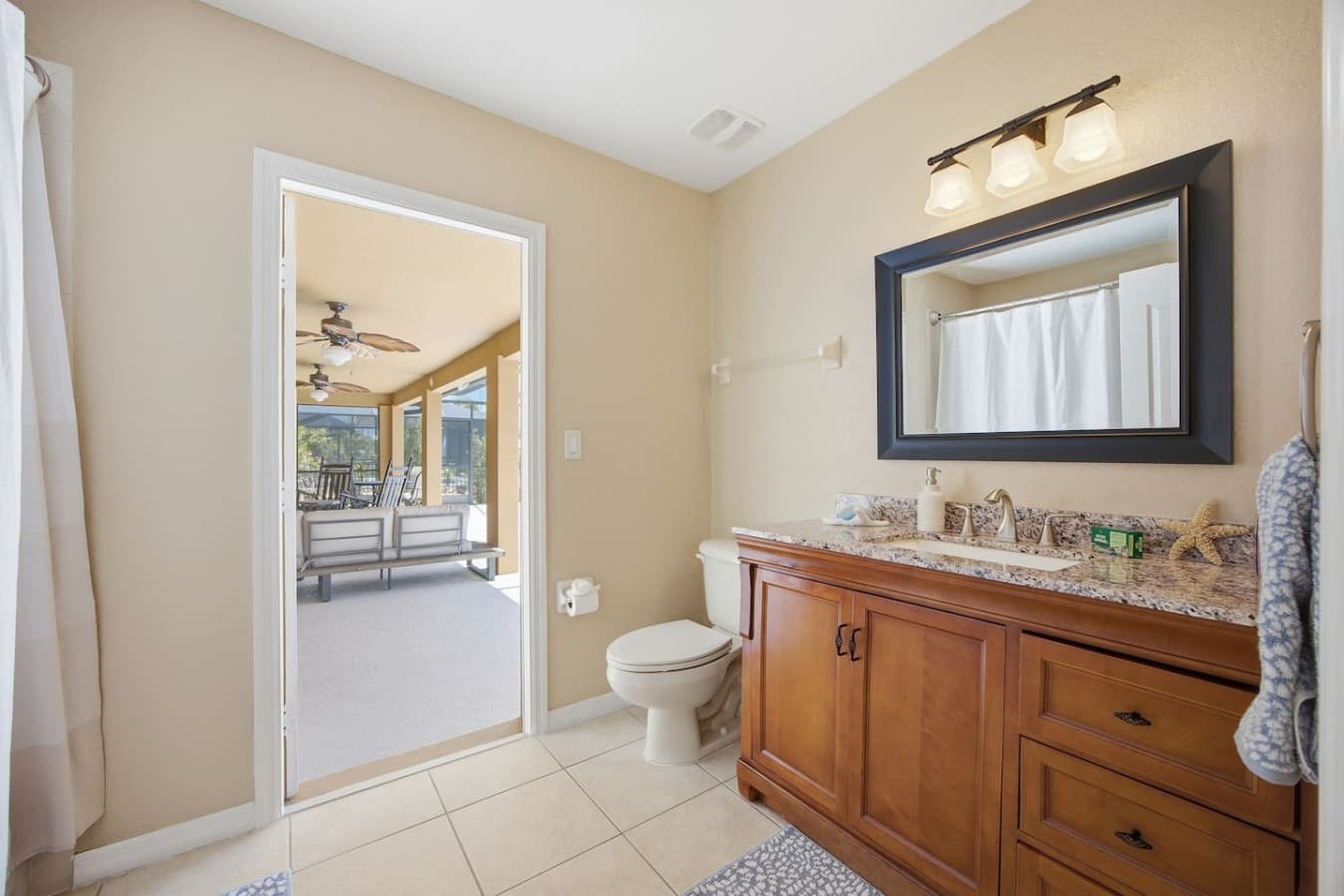 Full bathroom with a granite vanity, tub and shower combination, and direct access to the lanai.