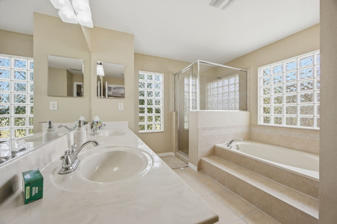 Well-appointed primary bathroom offering dual vanities, a separate shower, and a spacious soaking tub.