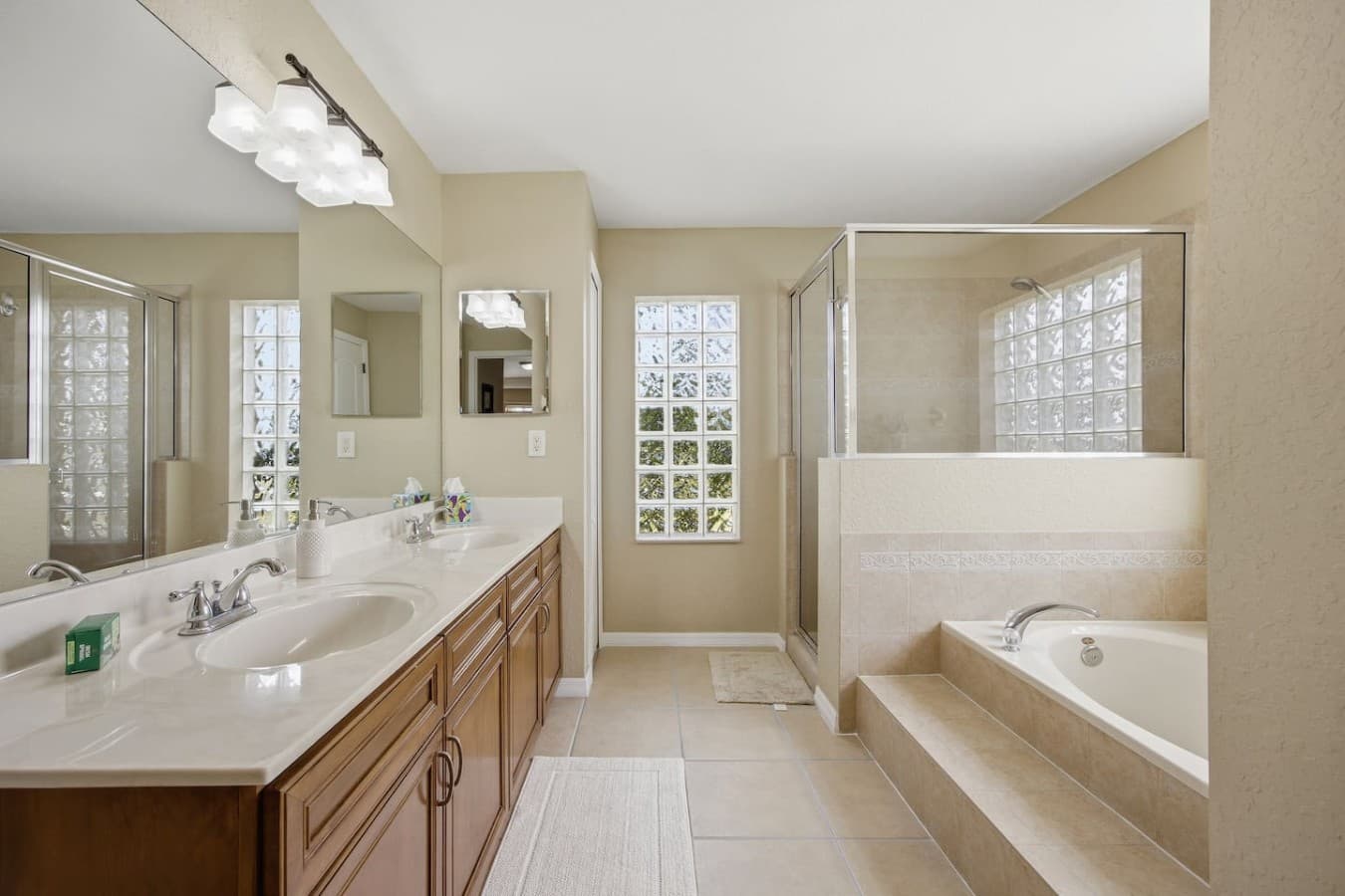 Spacious primary bathroom with dual vanities, a soaking tub, and a walk-in shower.