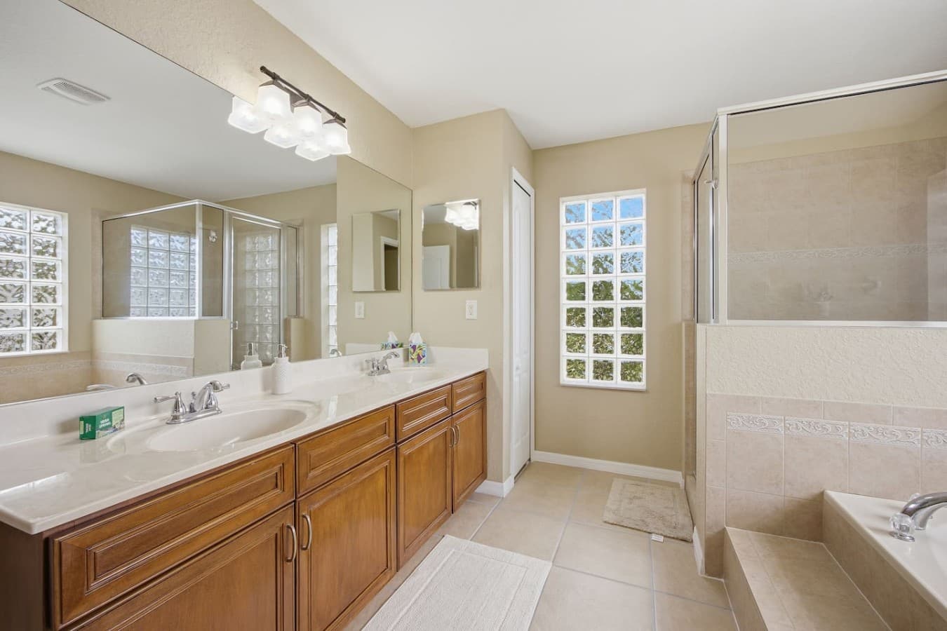 Bright ensuite bathroom featuring double sinks, ample counter space, and elegant finishes.