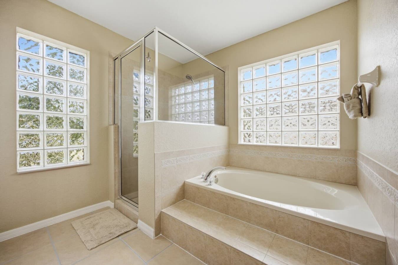 Luxurious bathroom with a glass-enclosed shower, relaxing soaking tub, and glass block windows.