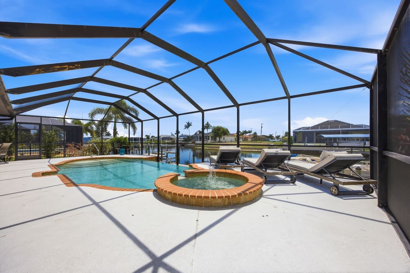 Spacious pool deck with a raised spa, lounge chairs, and panoramic waterfront views.