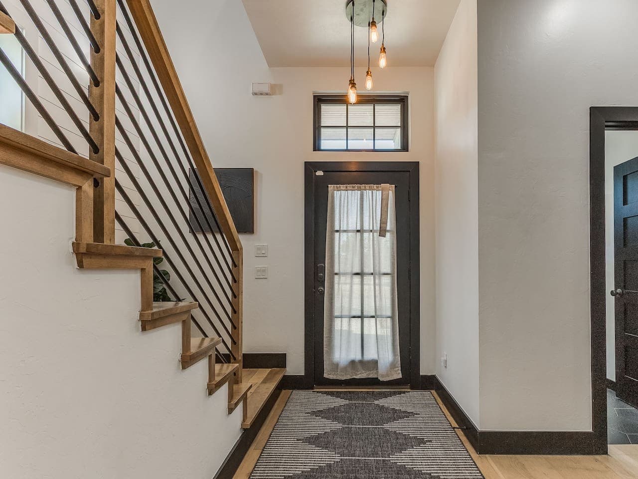 Bright front entry with modern lighting and a stylish staircase leading to the upper level.