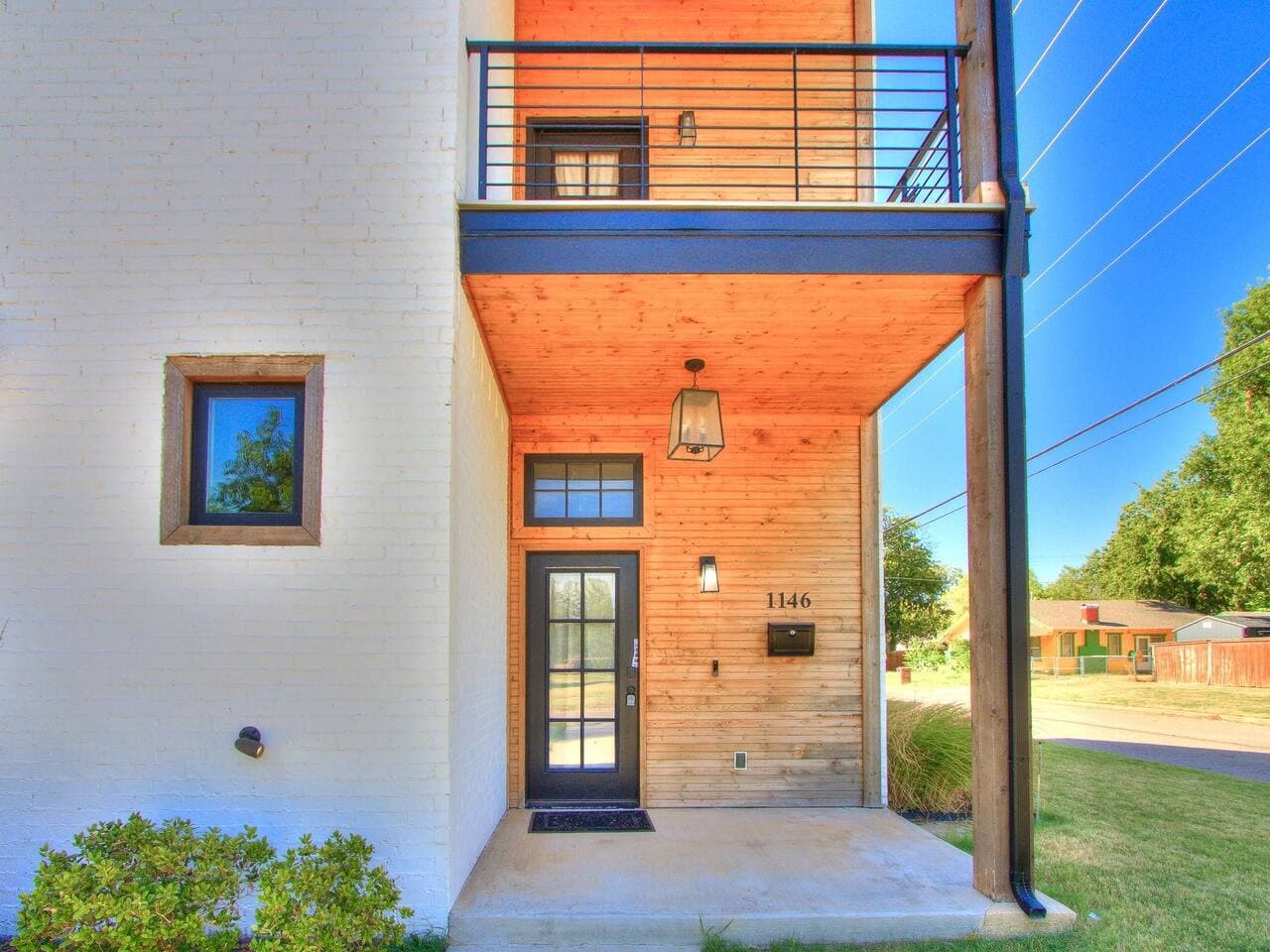 Welcoming front entrance with warm wood finishes and a private balcony overlooking the surrounding neighborhood.