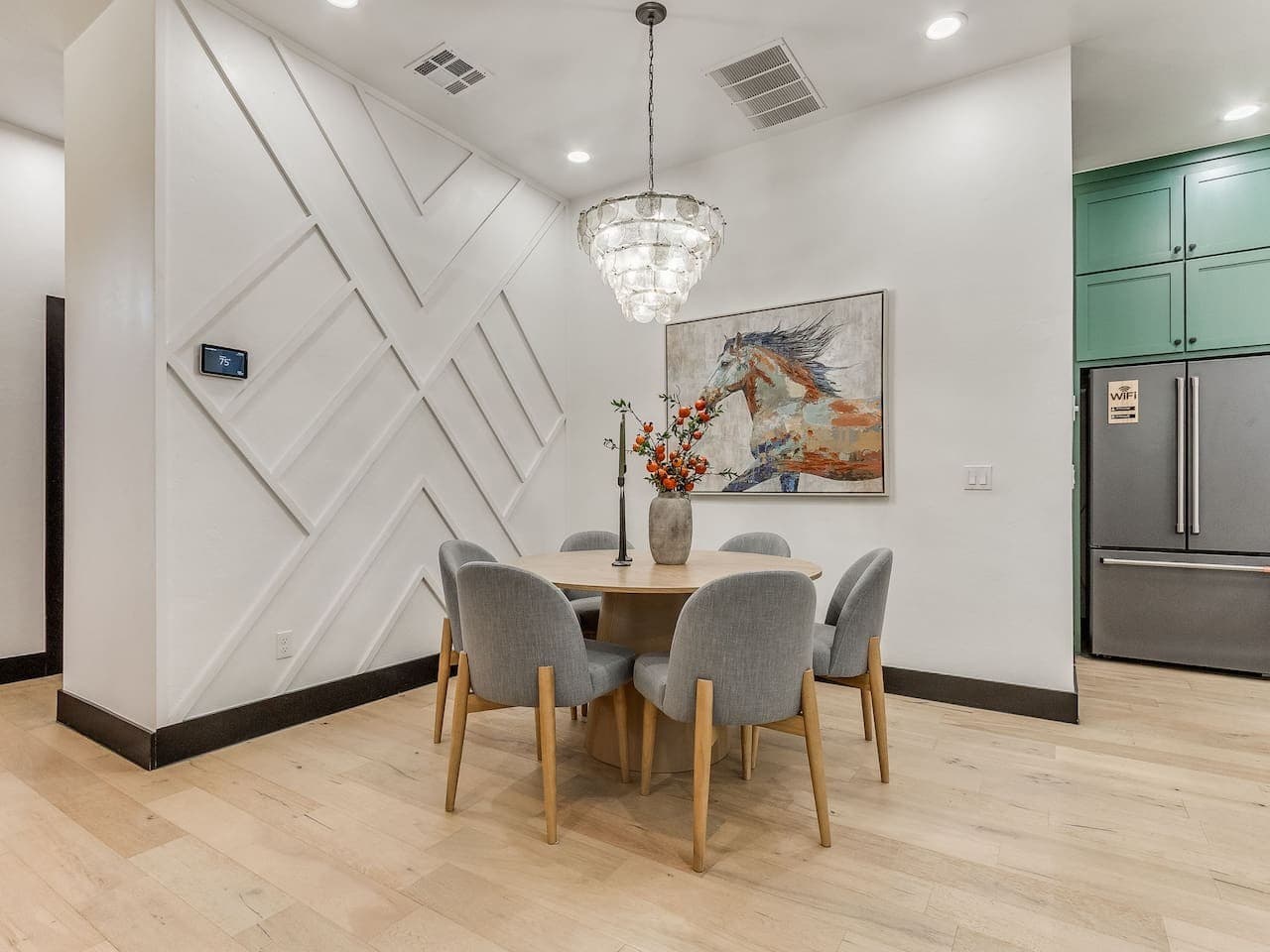 Elegant dining area with seating for six beneath a statement chandelier and contemporary artwork.