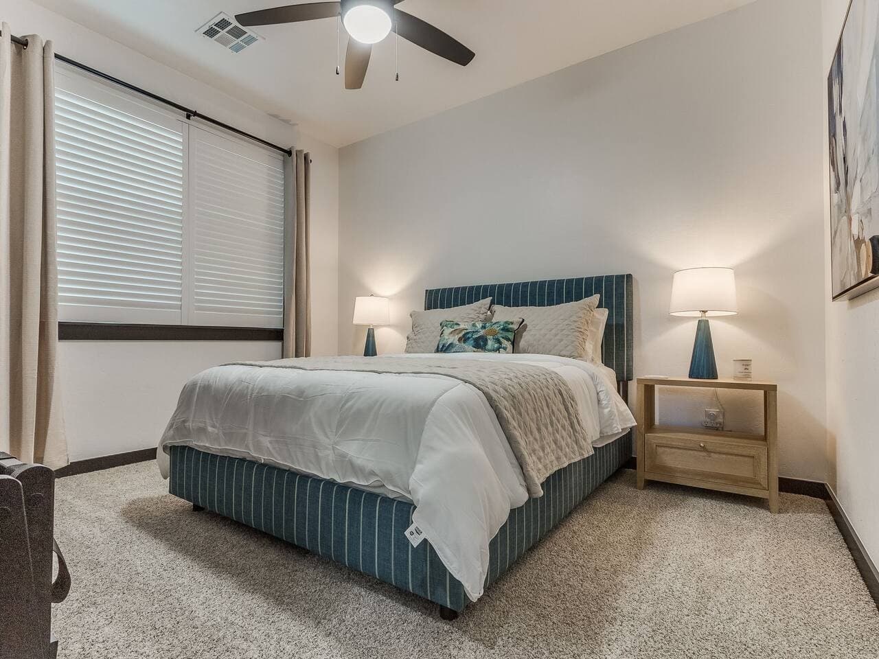 Cozy guest bedroom with a comfortable bed, soft linens, and warm bedside lighting.