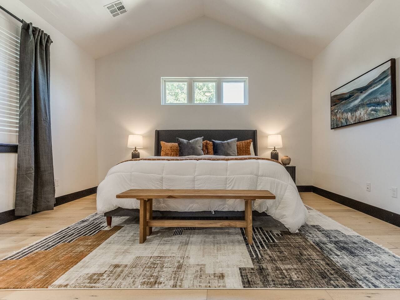 Spacious primary bedroom with a plush king bed, vaulted ceilings, and a warm inviting atmosphere.
