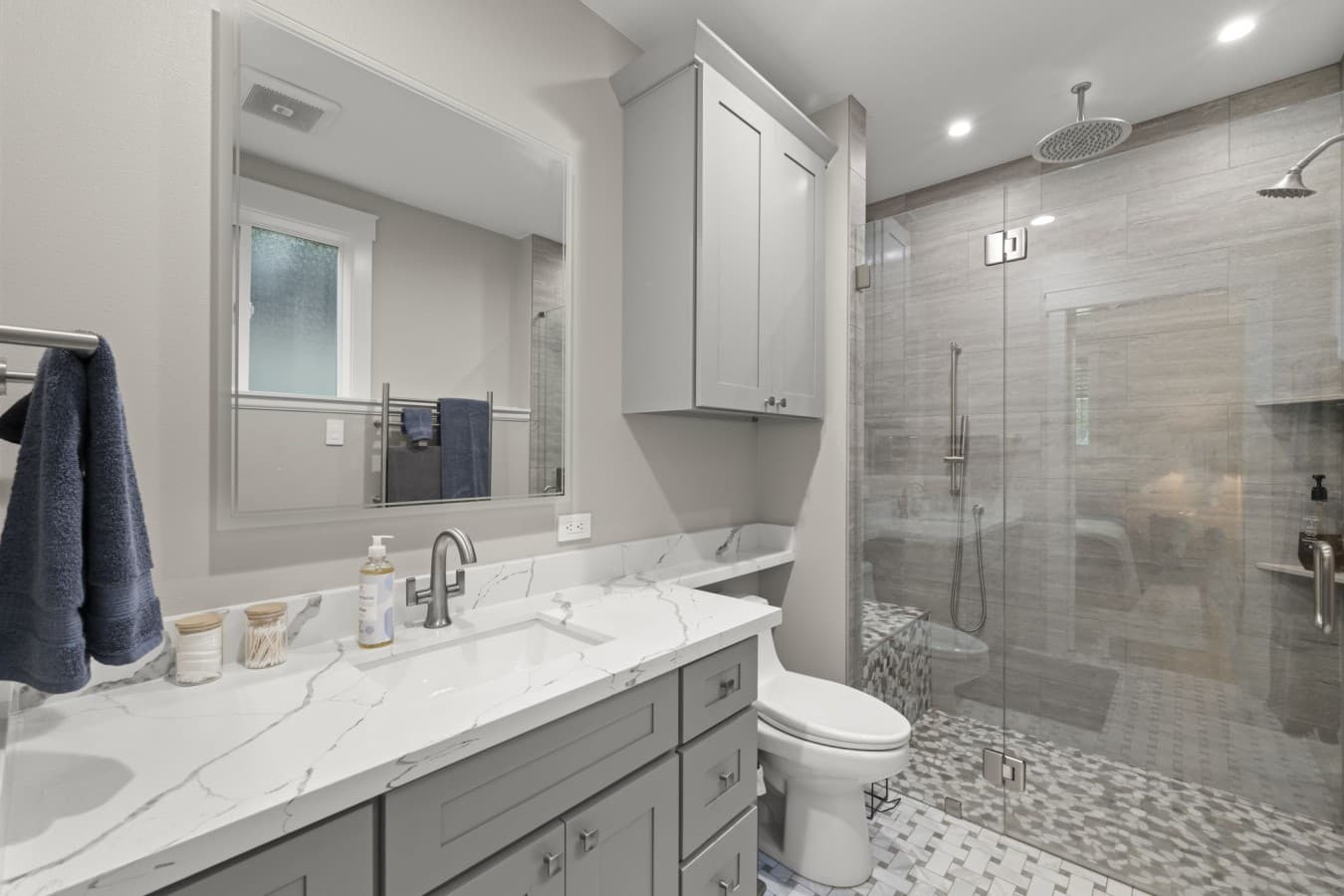 Spacious ensuite bathroom with a double vanity, toilet, and glass-enclosed walk-in shower with a rainfall showerhead_.jpg
