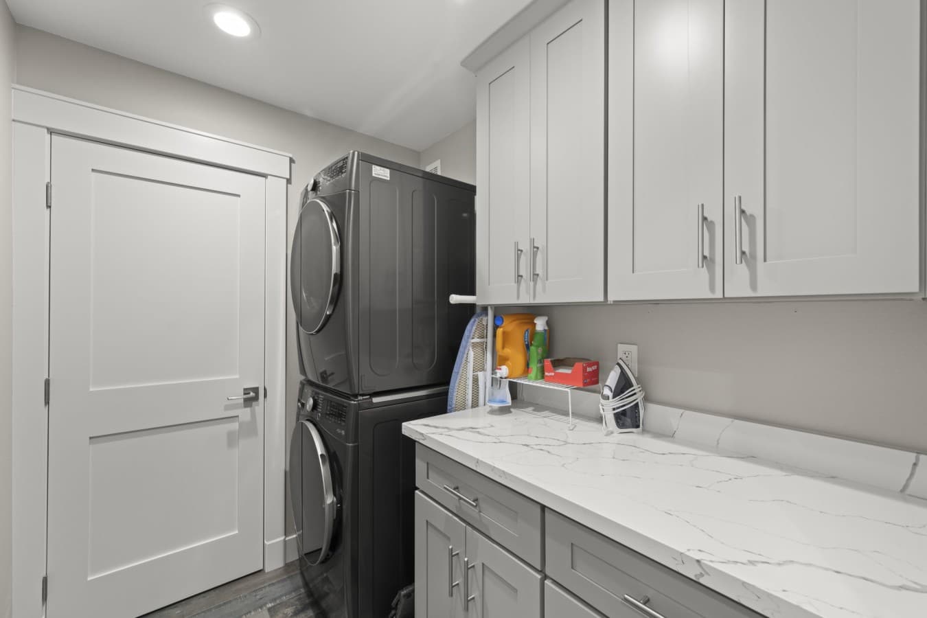 Convenient in-unit laundry area with a stacked washer and dryer, countertop, storage cabinets, and ironing essentials_.jpg