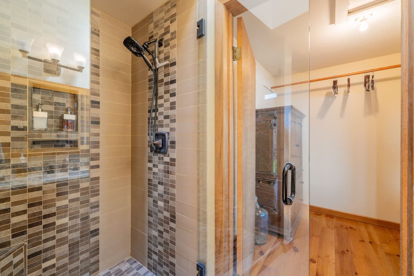 A bright, well-appointed bathroom featuring a granite vanity, warm wood finishes, and a spacious walk-in shower.