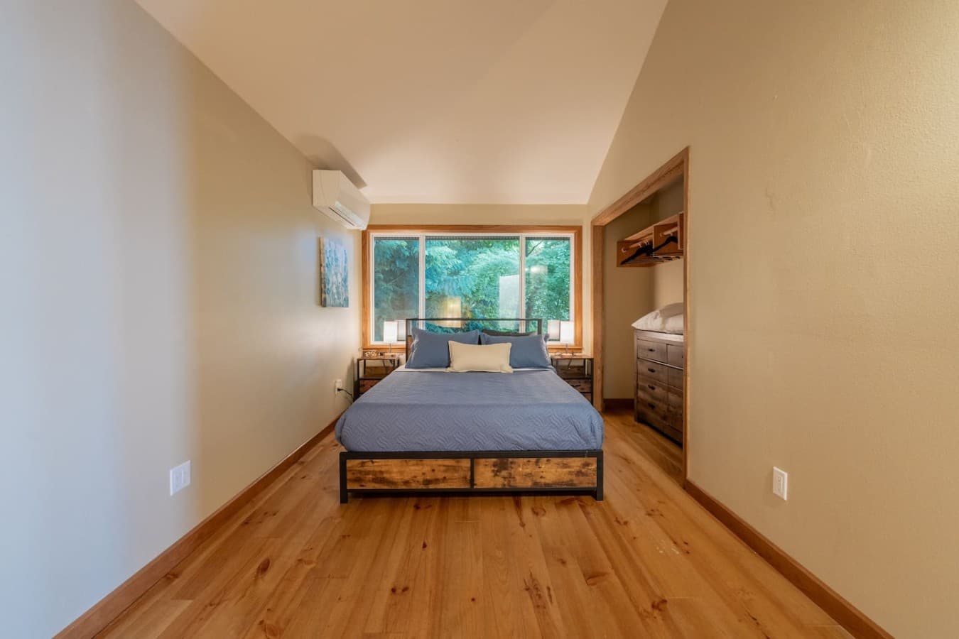 A peaceful bedroom retreat framed by lush green views and warm natural finishes.