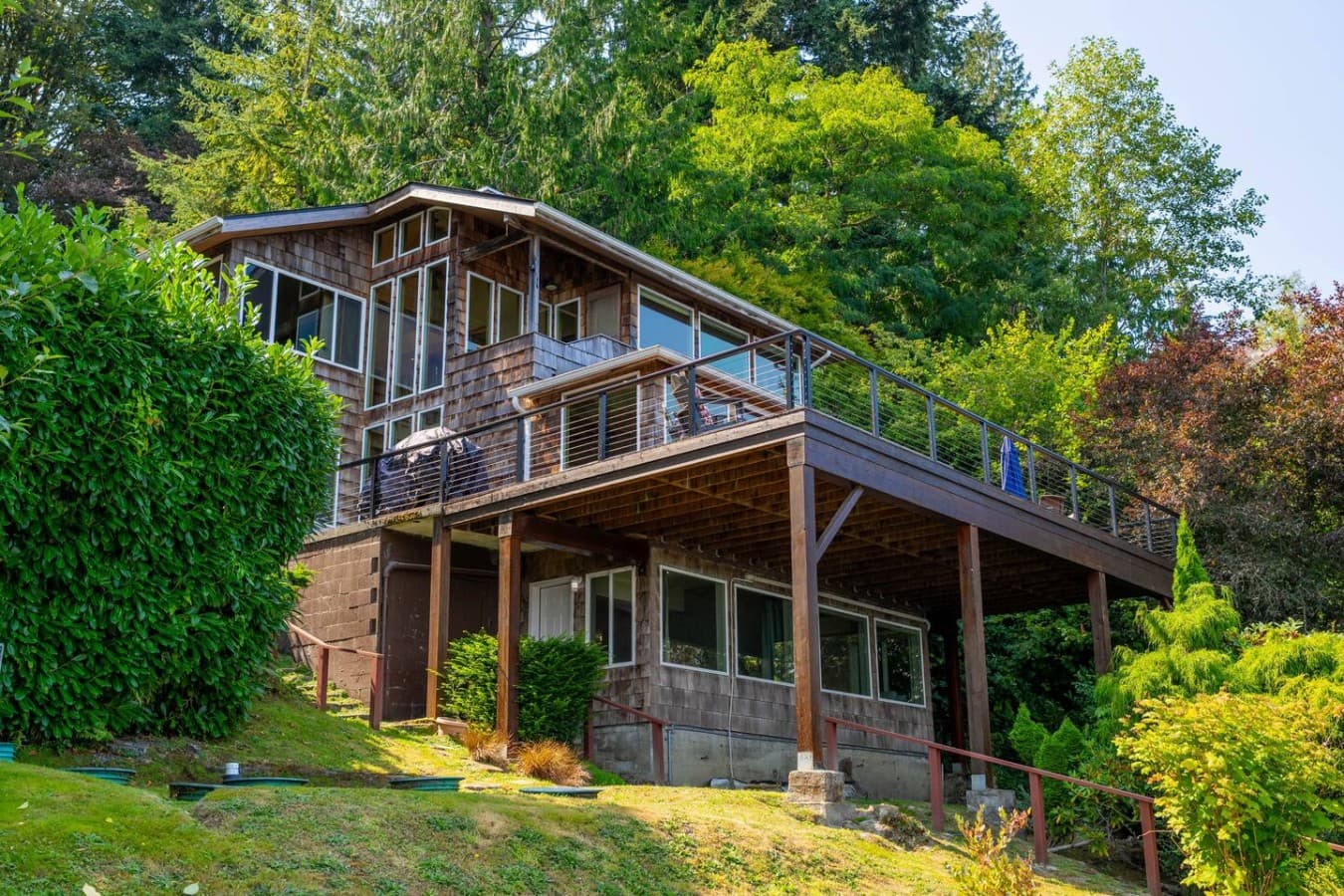 A secluded waterfront retreat surrounded by lush greenery, featuring expansive decks and multiple levels designed to take in the peaceful natural setting.