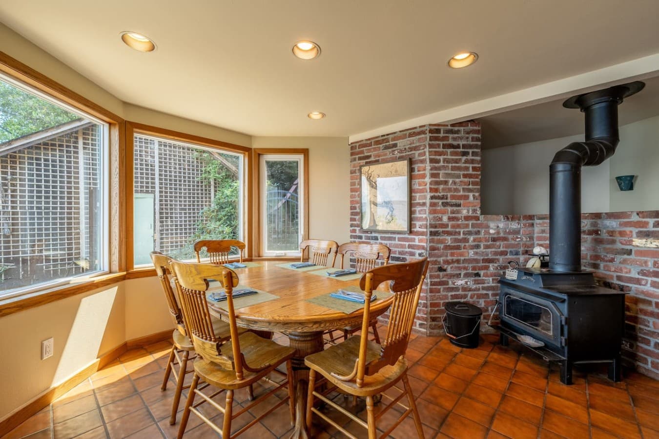 Gather around the dining table for memorable meals, with natural light, warm wood details, and a cozy wood-burning stove setting the scene.