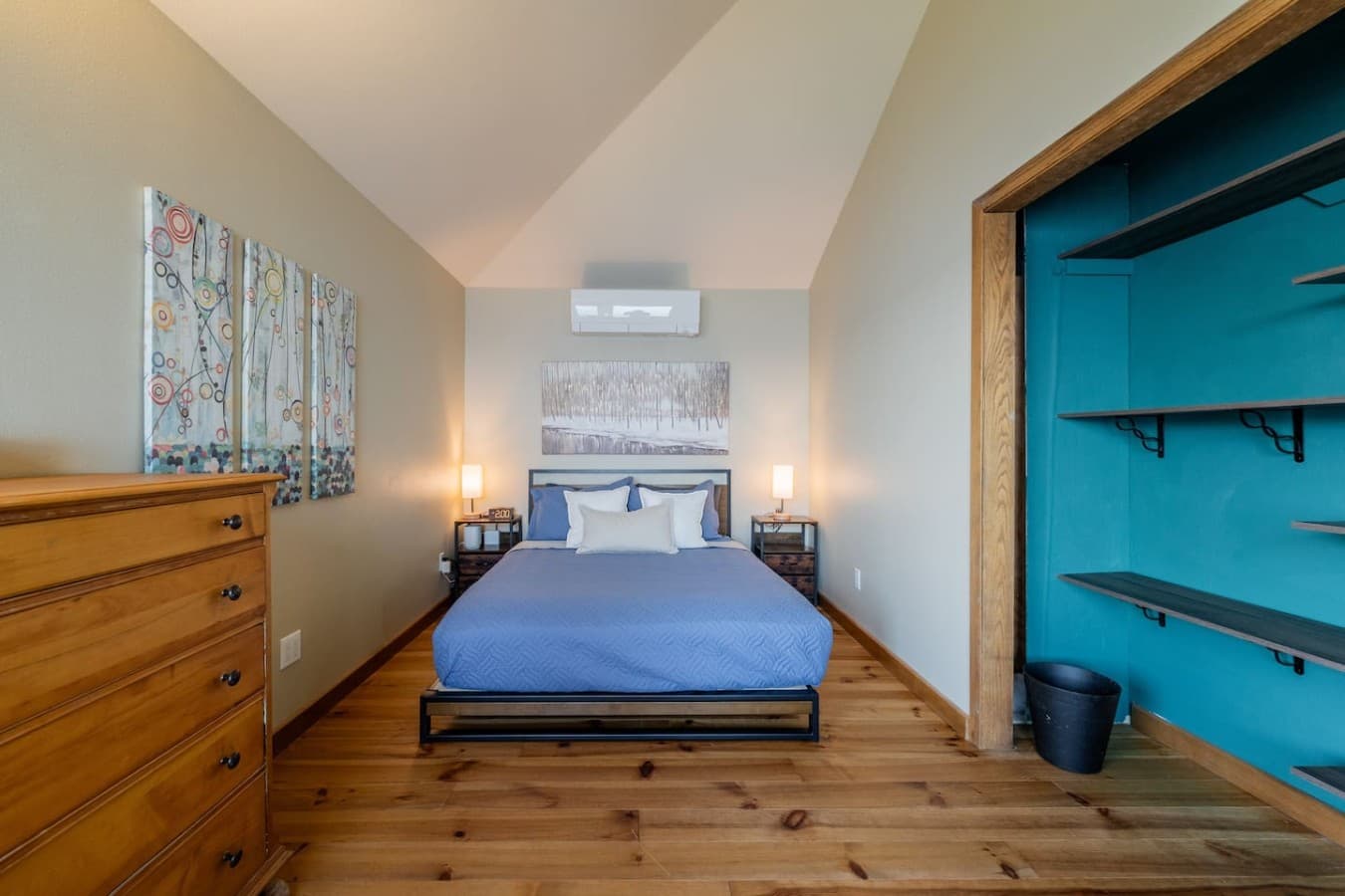 A comfortable, light-filled bedroom with warm wood floors, a spacious open closet, and thoughtful storage for settling in and feeling right at home.