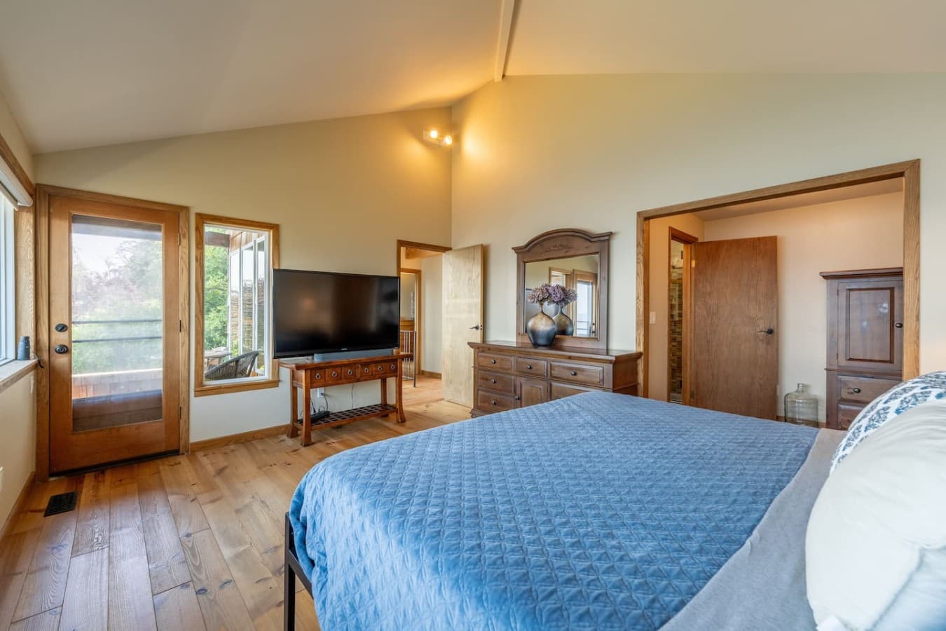 A spacious, light-filled bedroom with warm wood finishes, a private deck entrance, and plenty of room to settle in and unwind.