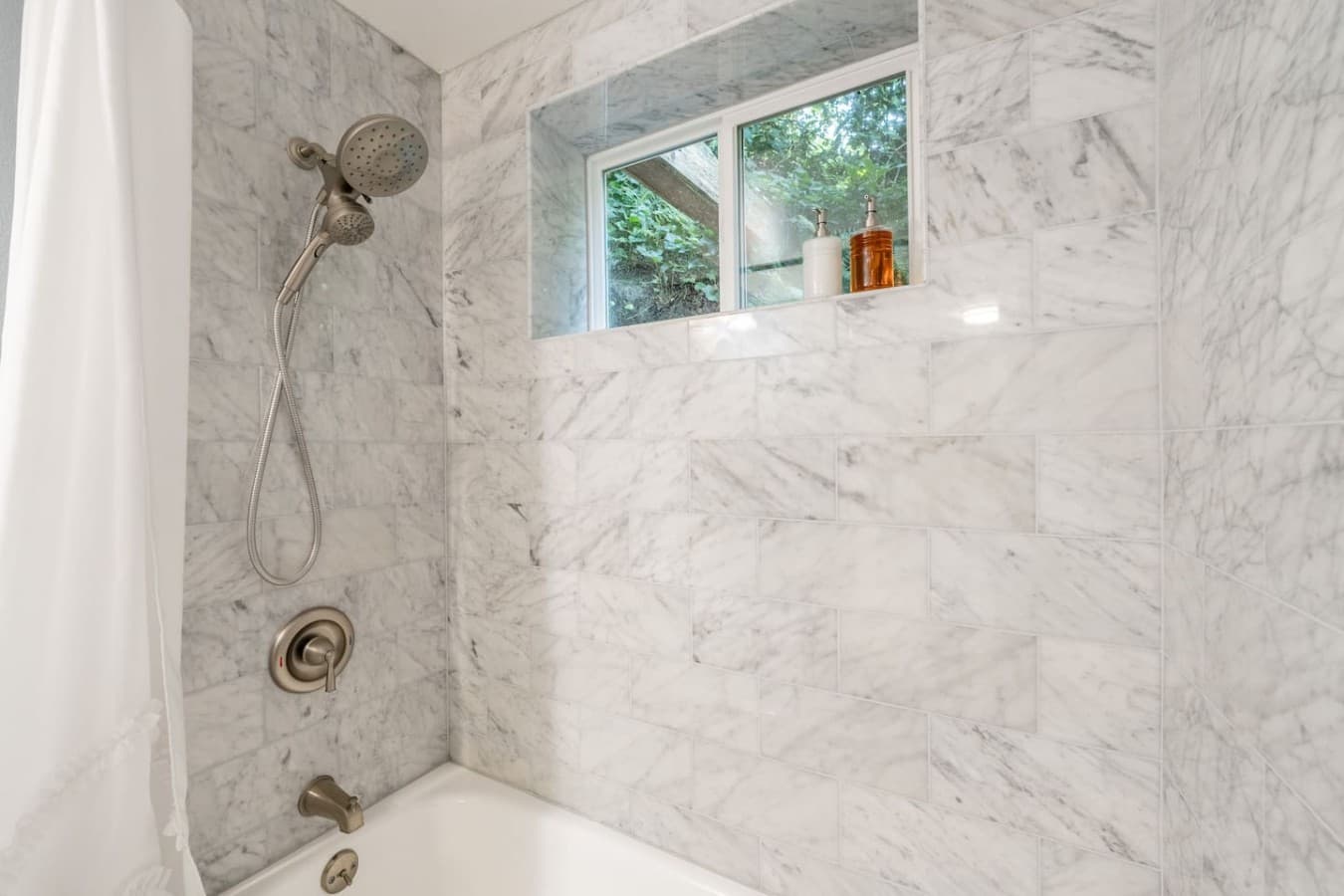 Modern comfort with classic touches, featuring a marble-style vanity and tiled tub/shower combination