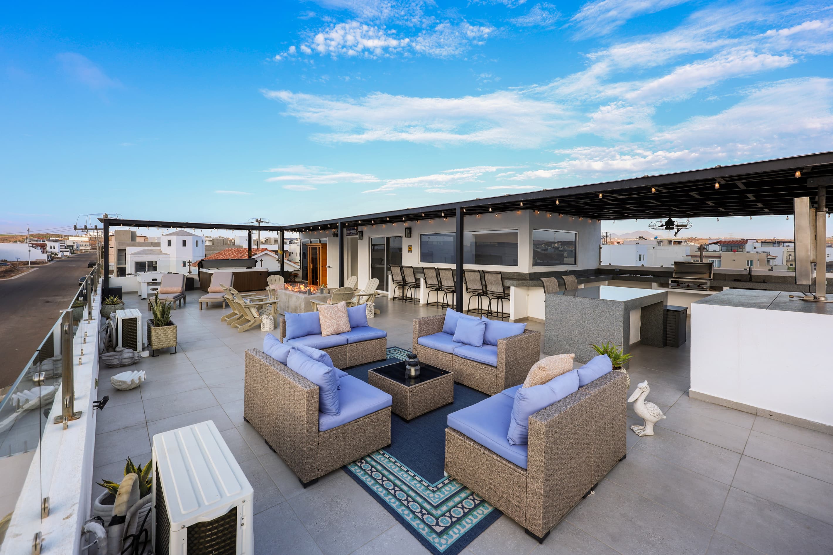 Expansive rooftop terrace with multiple lounge areas for relaxing and gathering, including a hot tub, sauna, firepit, foosball, Smart TV and outdoor kitchen with grill