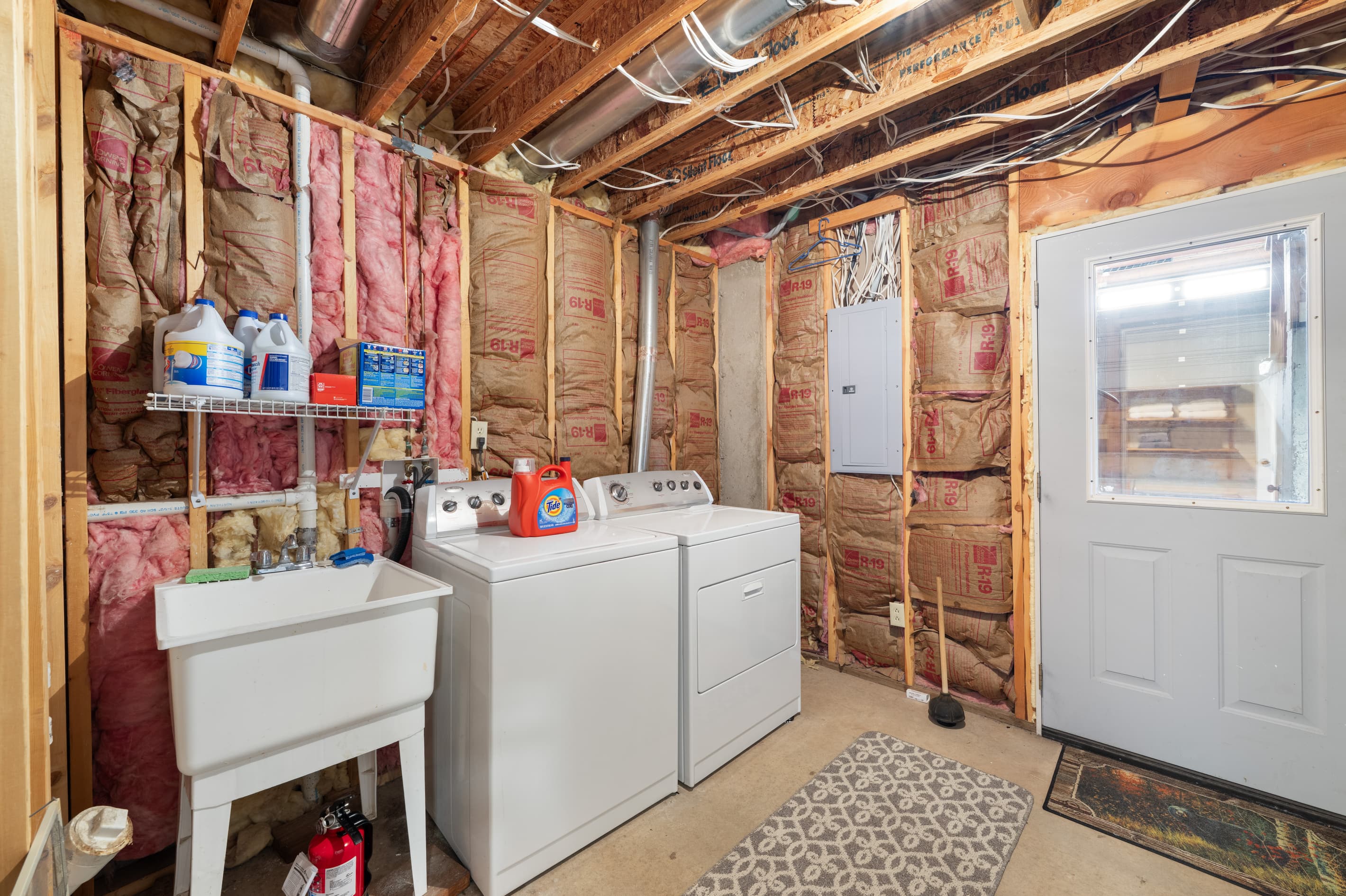 Unfinished laundry room with laundry sink & full sized washer & dryer. This room is accessed through lower bathroom. Access to lower mud-room out the other side. 