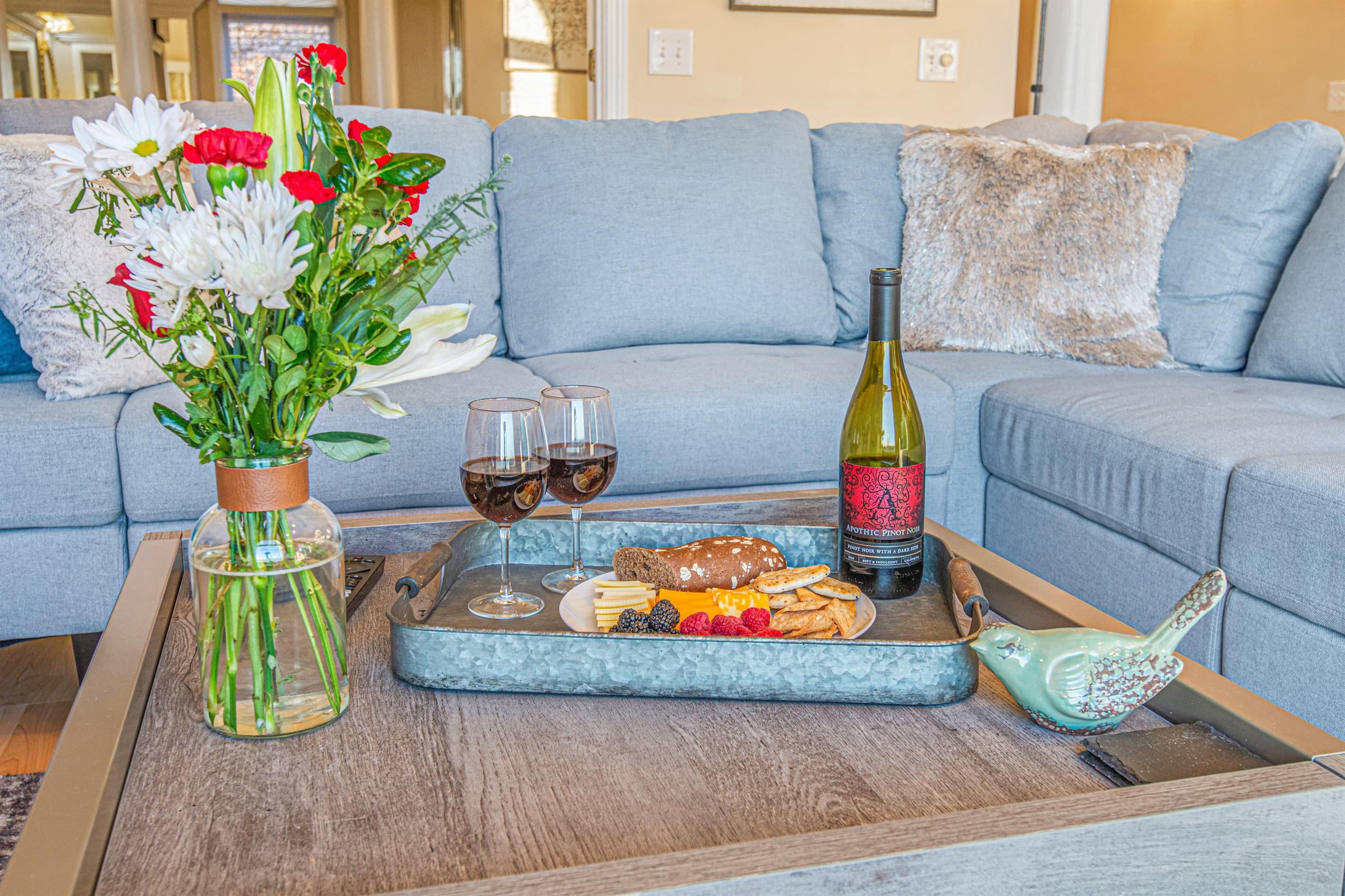 Living Room Delight: Sip wine amidst vibrant blooms and delectable treats on a stylish coffee table!