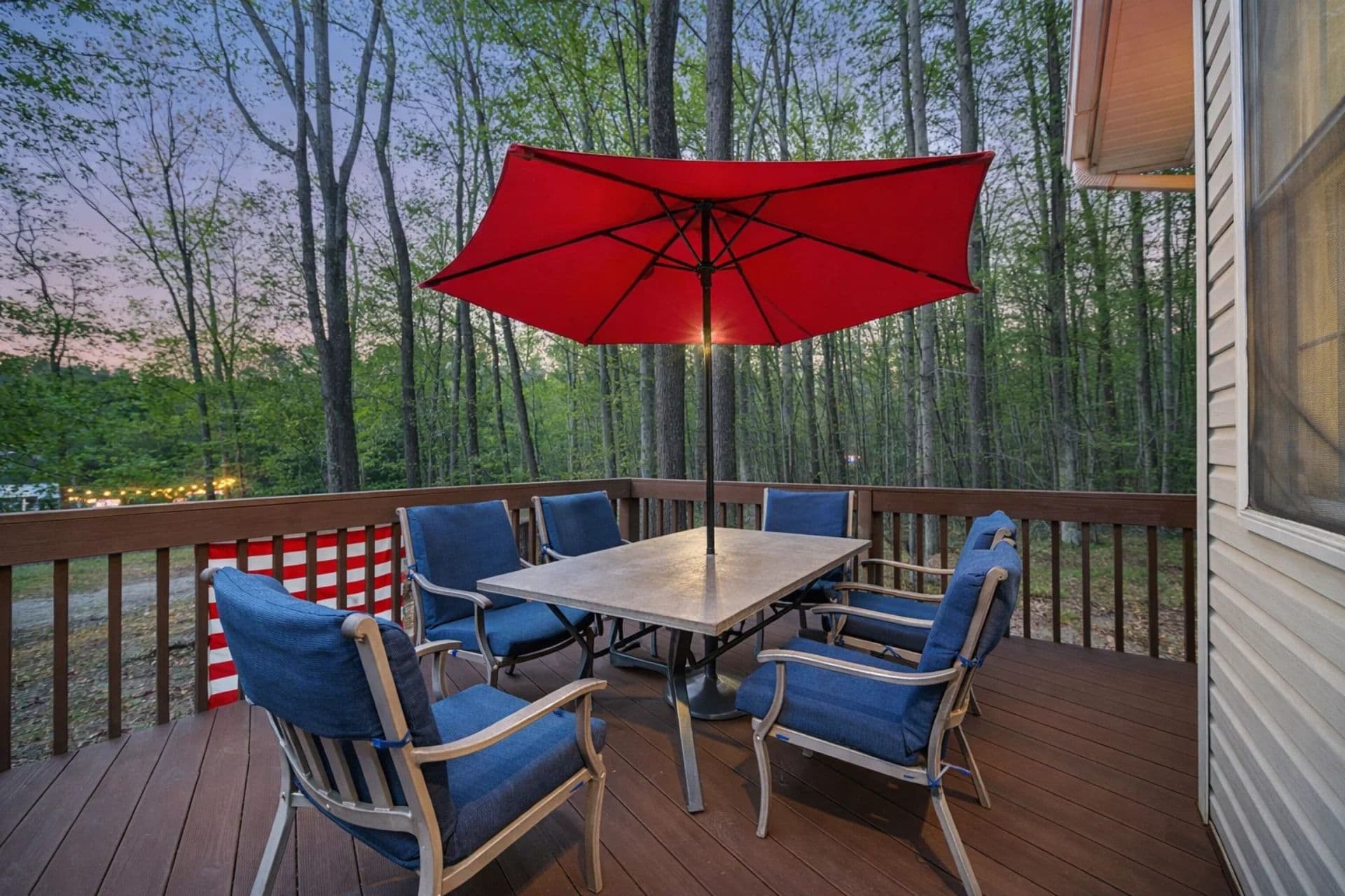 Outdoor Dining Retreat: Enjoy meals under a vibrant red umbrella amidst lush forest views!
