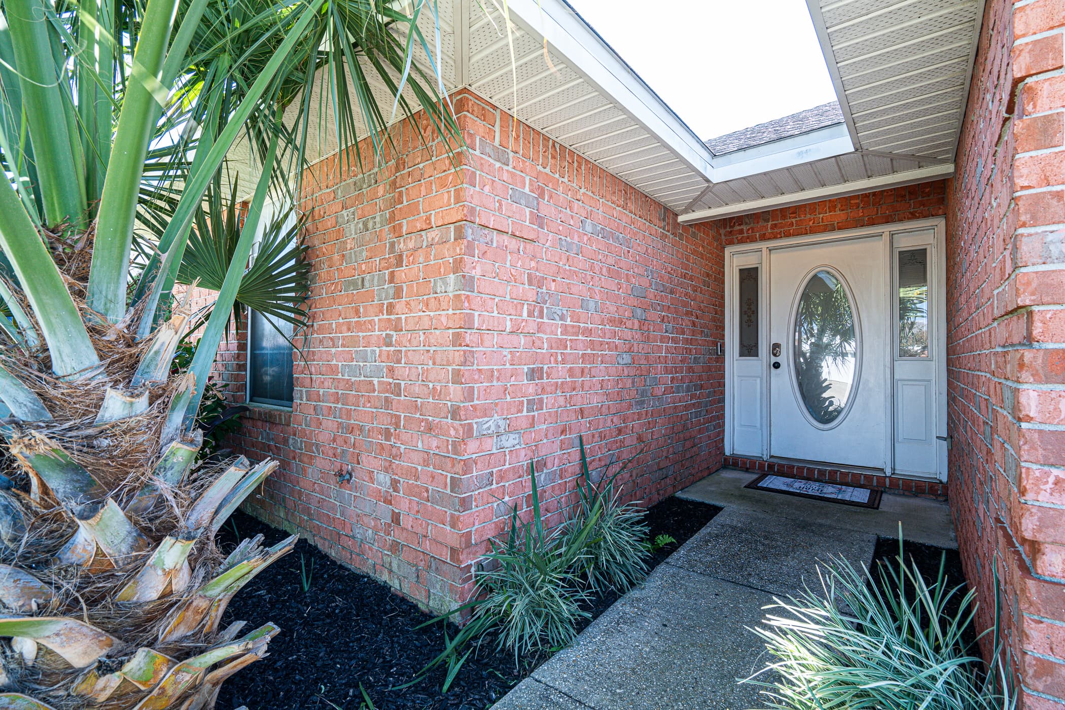Entryway: Welcome to your tropical retreat, graced with lush greenery and charming brickwork!