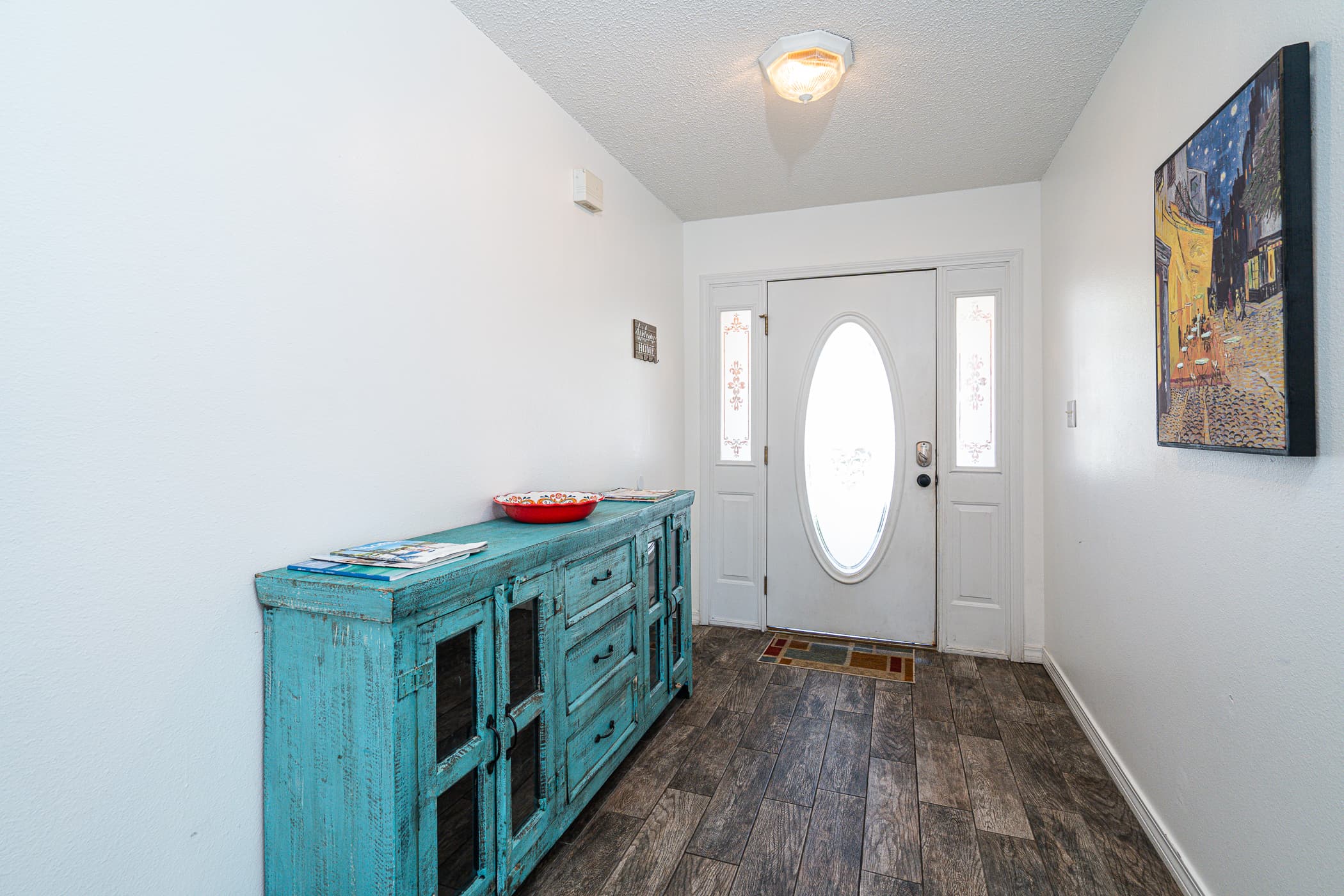 Entryway: Bright and welcoming, featuring a vibrant turquoise console and a charming art piece!