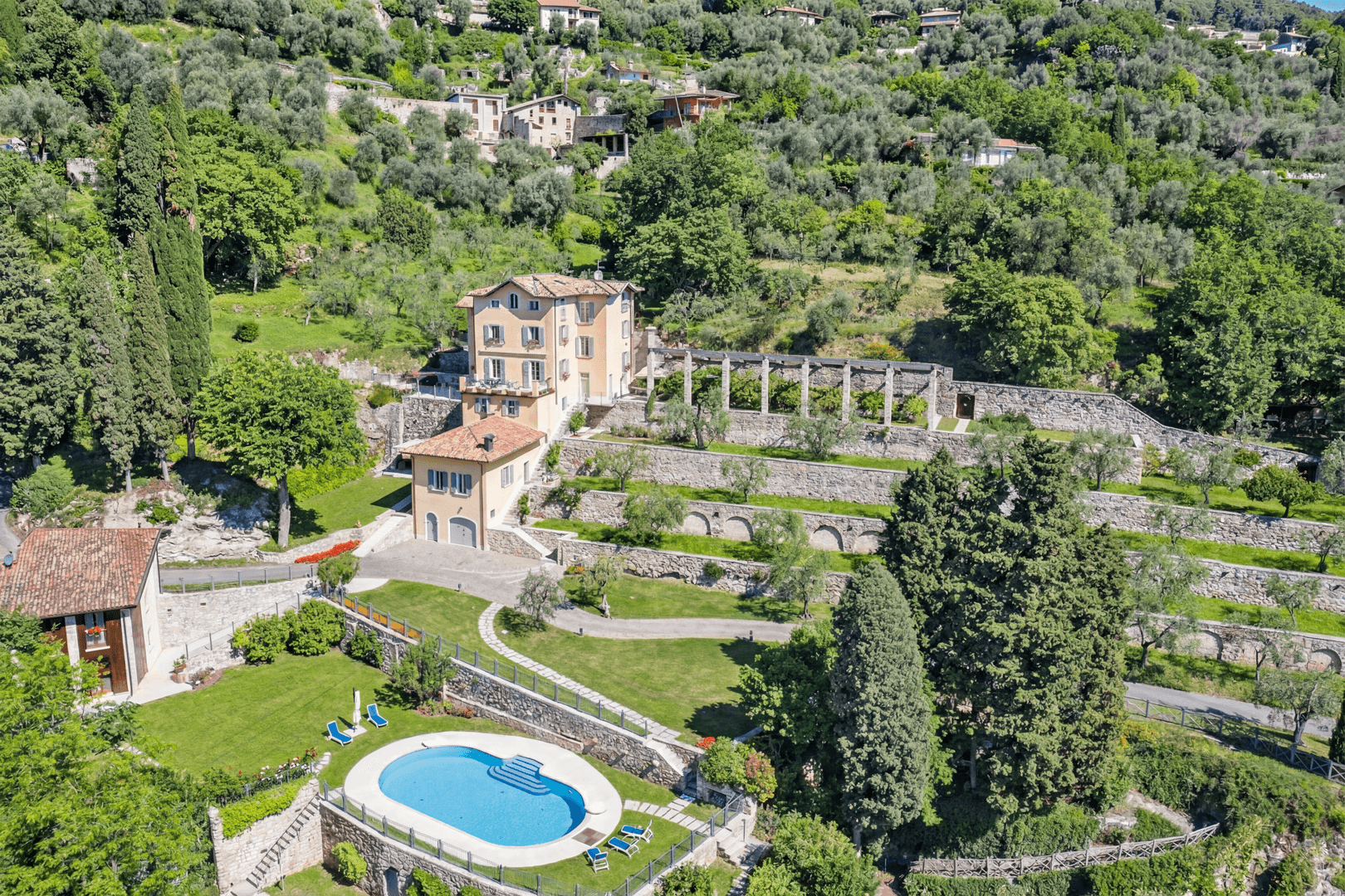A photo from above of the lemon house complex with the swimming pool, large green spaces and olive trees. 