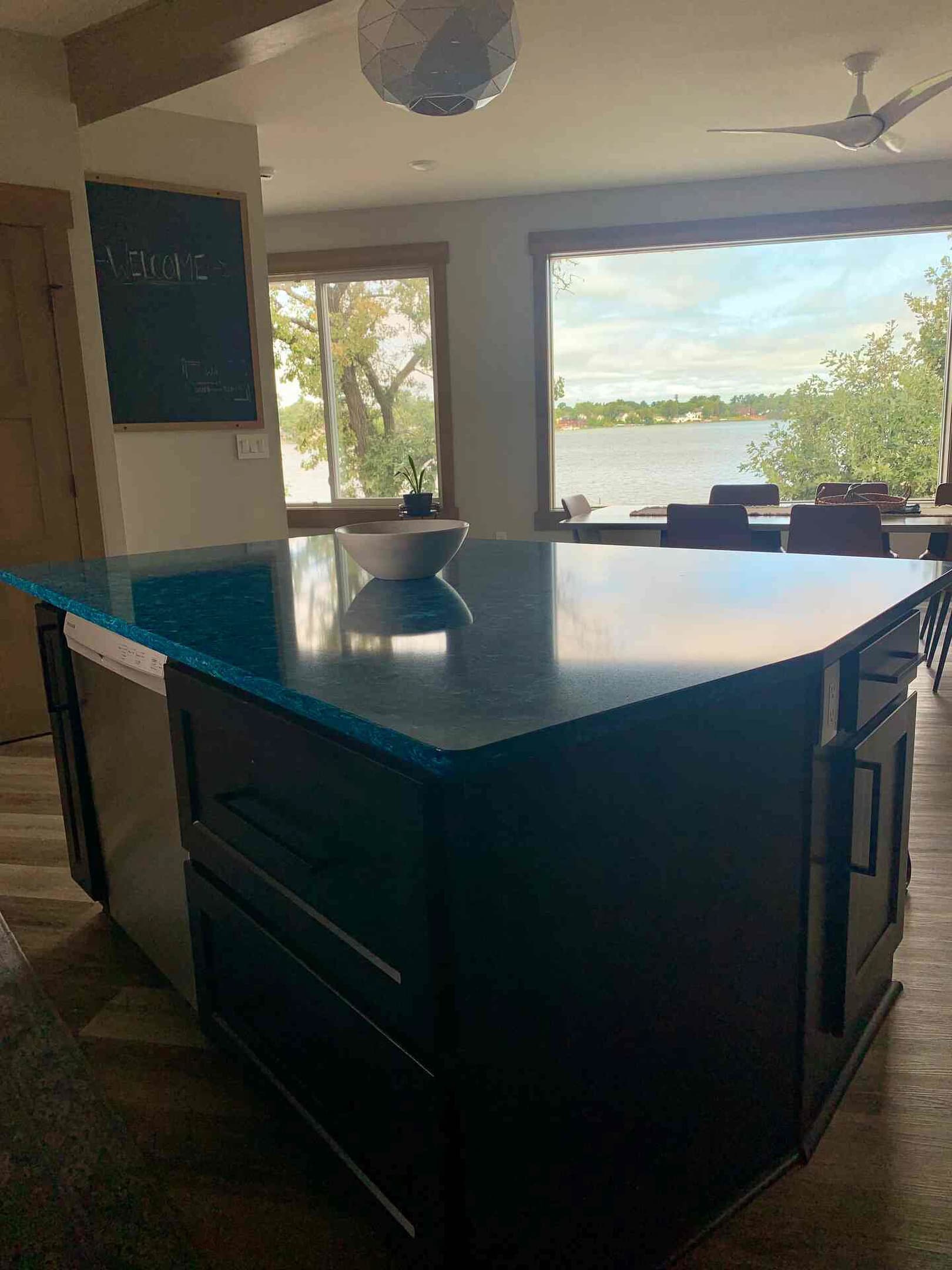 Open concept kitchen/dining with unique quartz countertop island paired with lake views.