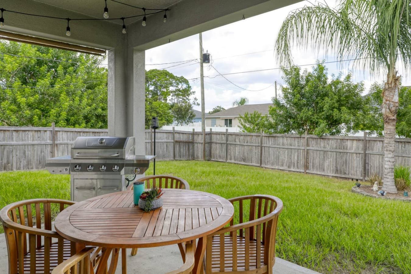 The covered patio offers a comfortable place to gather, grill, and enjoy meals overlooking the fenced backyard.