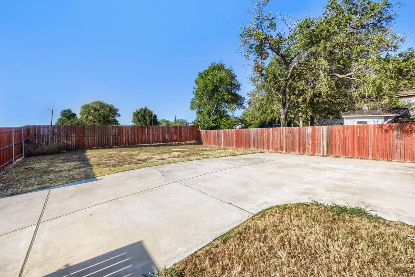 Enjoy fresh air in the spacious fenced backyard, featuring a large paved patio and open lawn for outdoor fun.