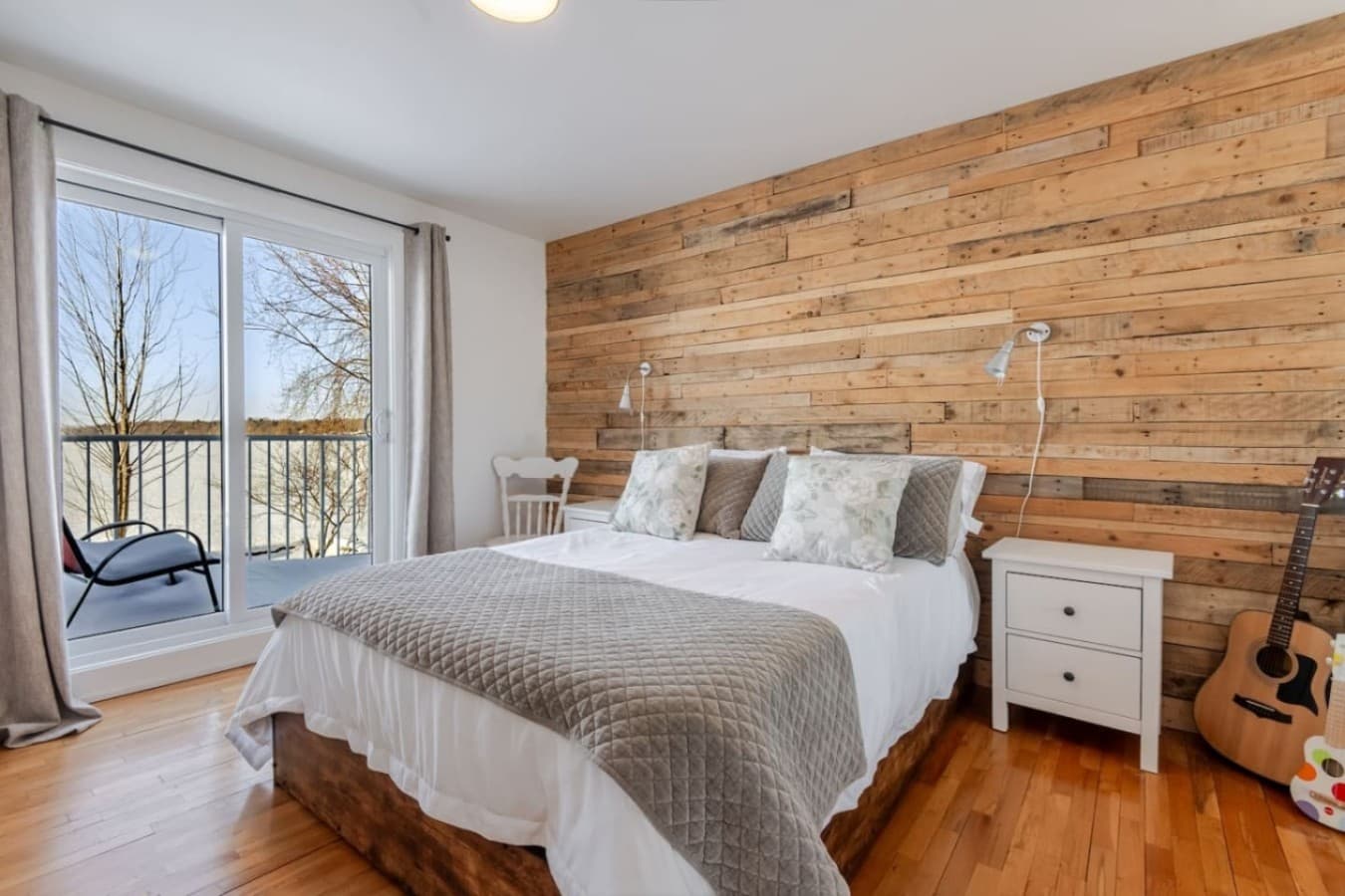 Chambre principale spacieuse avec lit King-size et balcon offrant une vue imprenable sur l'eau
