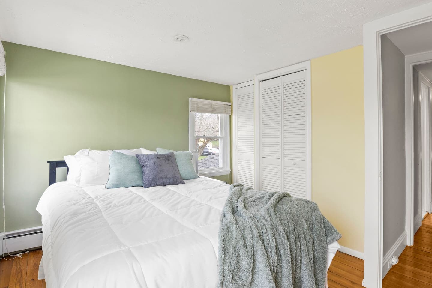 Green bedroom with white door closet and neutral bedding